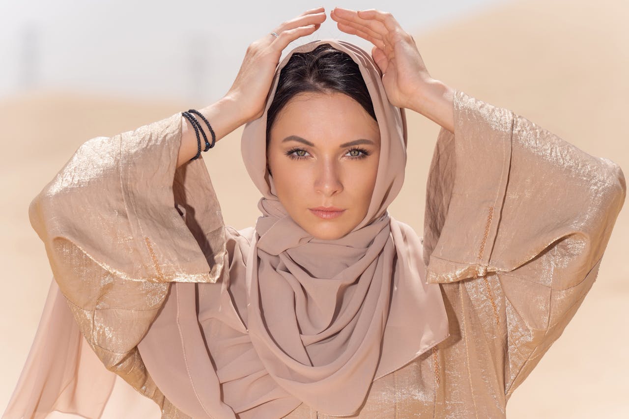 Portrait of a woman in a hijab, posing gracefully in the Dubai desert.
